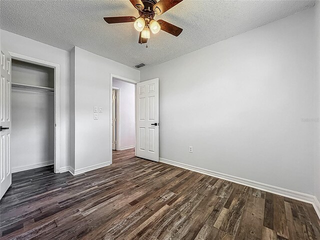 unfurnished bedroom with baseboards, dark wood finished floors, a textured ceiling, and visible vents