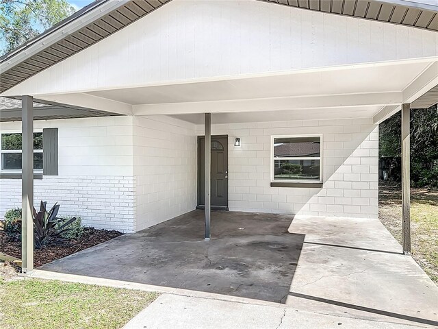 view of exterior entry with concrete block siding and an attached carport