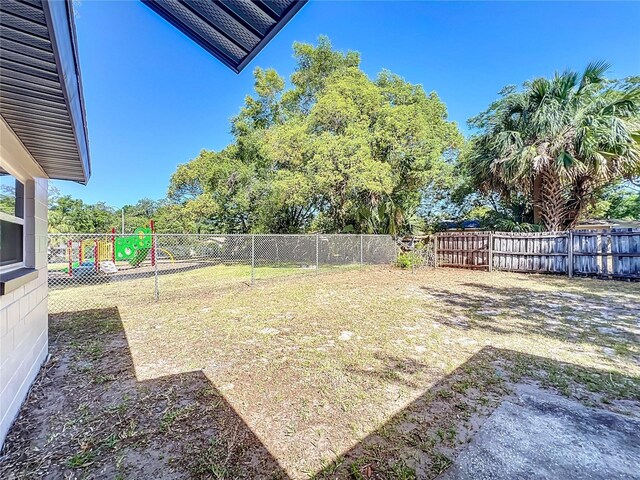 view of yard with a fenced backyard and a playground