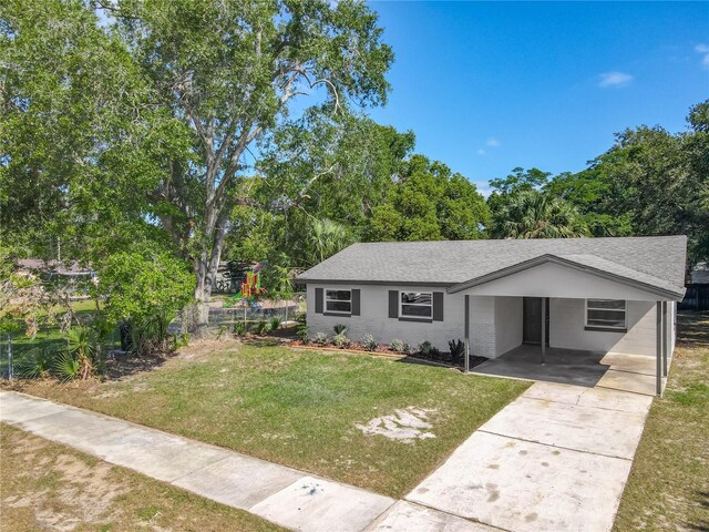 view of front of property featuring roof with shingles, concrete driveway, an attached carport, and a front lawn