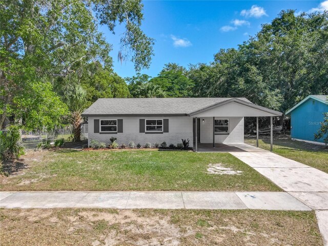 ranch-style home featuring concrete driveway, a front yard, and an attached carport