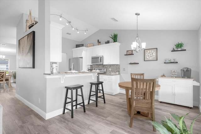 36700 Oconee Ave, Eustis, FL 32736 - kitchen with visible vents, a peninsula, a kitchen breakfast bar, a notable chandelier, and stainless steel appliances