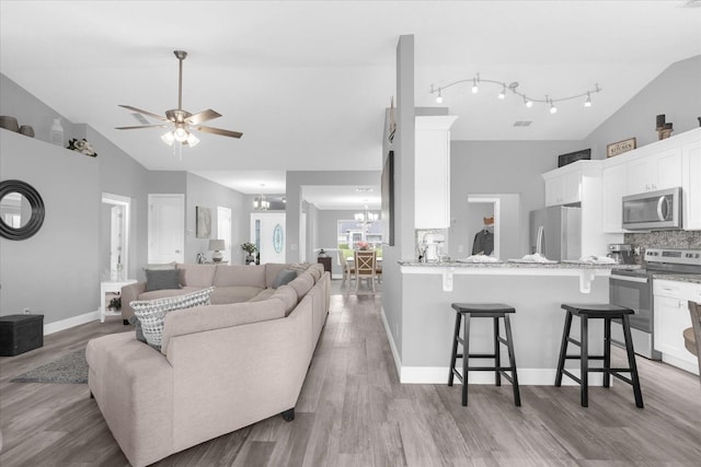 36700 Oconee Ave, Eustis, FL 32736 - living area featuring high vaulted ceiling, baseboards, ceiling fan with notable chandelier, and light wood-type flooring