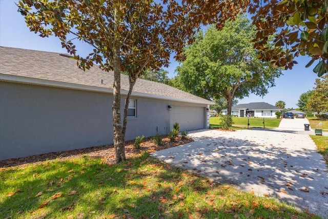 36700 Oconee Ave, Eustis, FL 32736 - view of side of property with a lawn, roof with shingles, stucco siding, concrete driveway, and an attached garage
