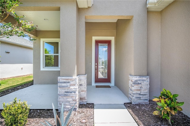 doorway to property featuring stucco siding and stone siding