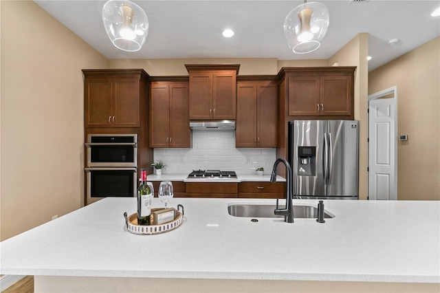 kitchen featuring decorative backsplash, light countertops, under cabinet range hood, a sink, and appliances with stainless steel finishes