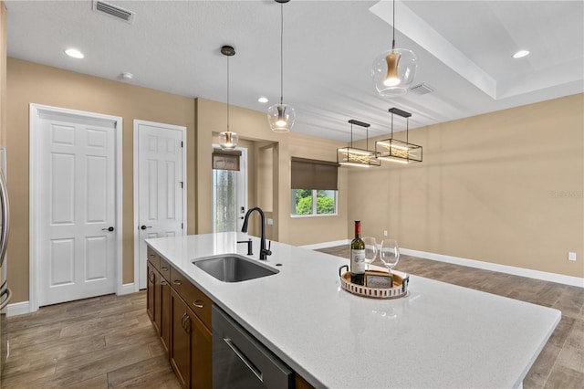 kitchen featuring a sink, dishwasher, baseboards, wood finished floors, and visible vents