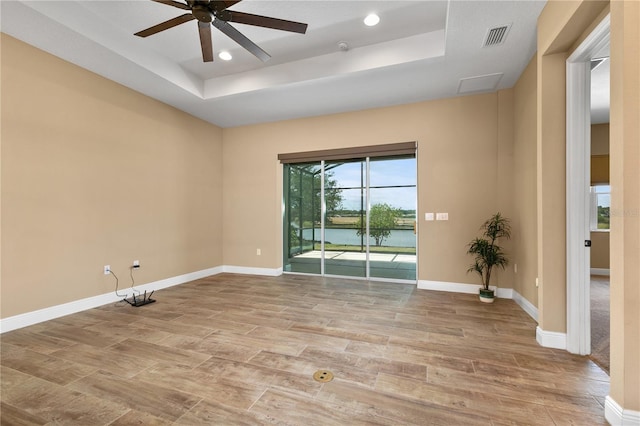 empty room featuring a tray ceiling, ceiling fan, visible vents, and recessed lighting
