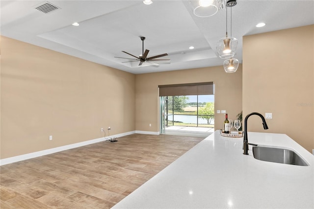 kitchen featuring visible vents, a ceiling fan, recessed lighting, a tray ceiling, and a sink