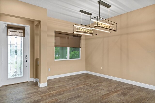 foyer entrance featuring dark wood-style flooring, baseboards, and a notable chandelier