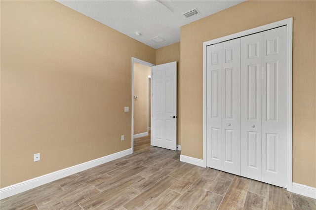 unfurnished bedroom with light wood-type flooring, baseboards, visible vents, and a closet
