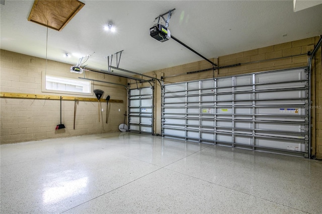 garage with a garage door opener and concrete block wall