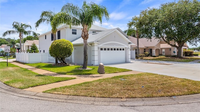 traditional home with driveway, fence, a garage, stucco siding, and a front yard