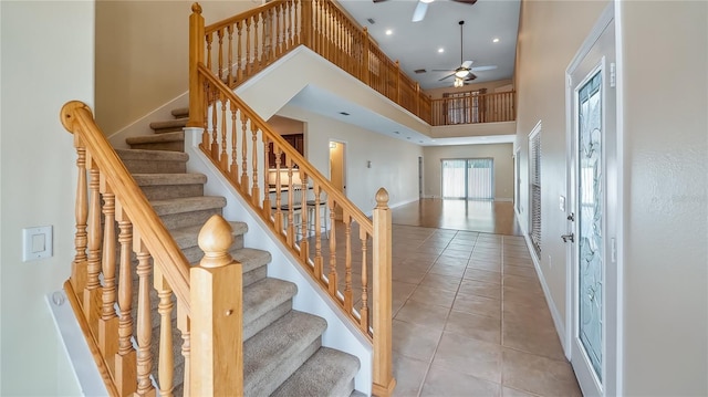 staircase featuring recessed lighting, tile patterned flooring, a ceiling fan, a high ceiling, and baseboards