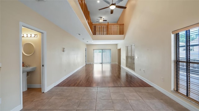 unfurnished living room with ceiling fan, light tile patterned flooring, a wealth of natural light, and baseboards
