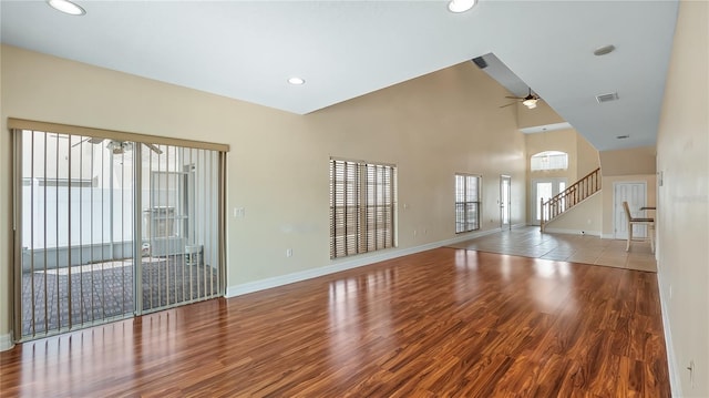 unfurnished living room featuring wood finished floors, visible vents, stairway, ceiling fan, and baseboards