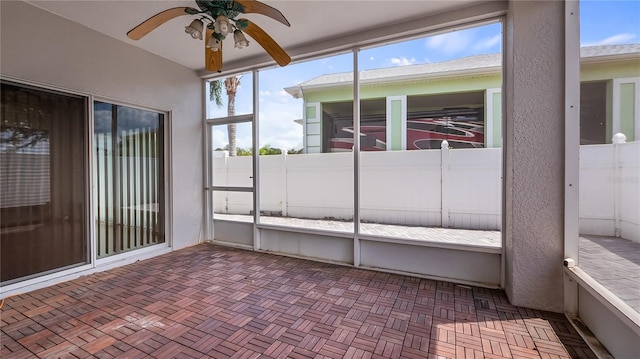 unfurnished sunroom featuring ceiling fan