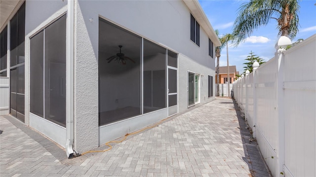 view of home's exterior featuring stucco siding, a sunroom, a fenced backyard, and a patio