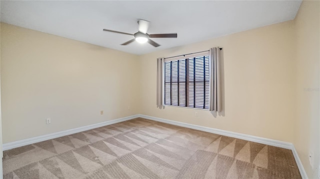 spare room with ceiling fan, light carpet, and baseboards