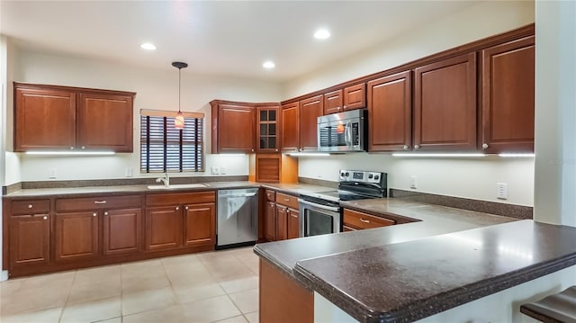 kitchen with a sink, stainless steel appliances, hanging light fixtures, and dark countertops