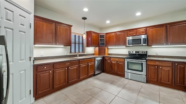 kitchen with a sink, pendant lighting, light tile patterned floors, dark countertops, and appliances with stainless steel finishes