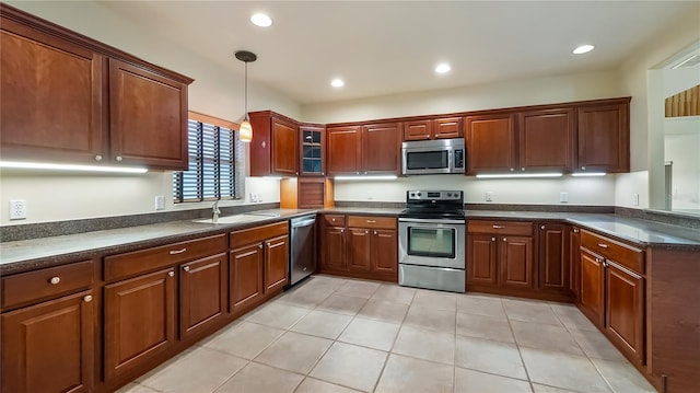 kitchen featuring pendant lighting, light tile patterned floors, a sink, dark countertops, and appliances with stainless steel finishes