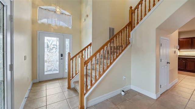 entrance foyer featuring light tile patterned floors, stairway, baseboards, and a towering ceiling