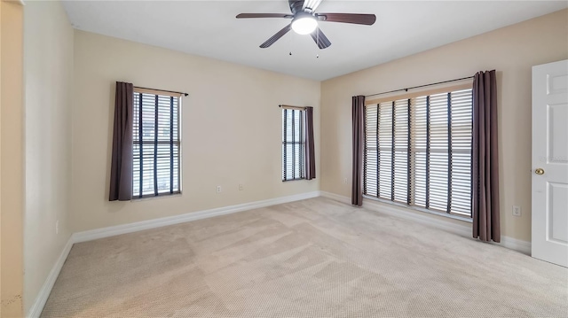 unfurnished room featuring light carpet, baseboards, and a ceiling fan