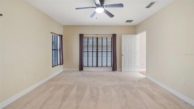empty room featuring light colored carpet, baseboards, a ceiling fan, and visible vents