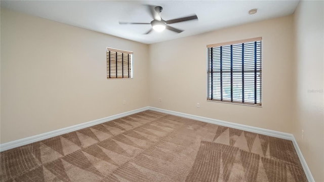spare room with a ceiling fan, a wealth of natural light, baseboards, and carpet