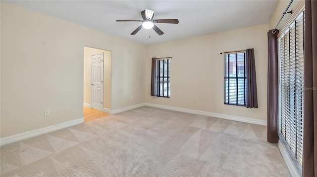 unfurnished room featuring plenty of natural light, light carpet, baseboards, and a ceiling fan