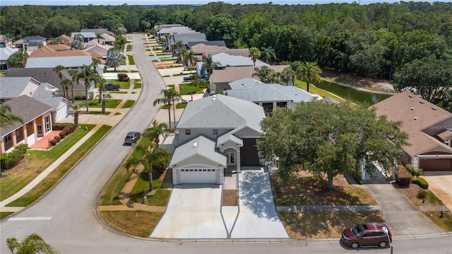 bird's eye view featuring a wooded view, a water view, and a residential view