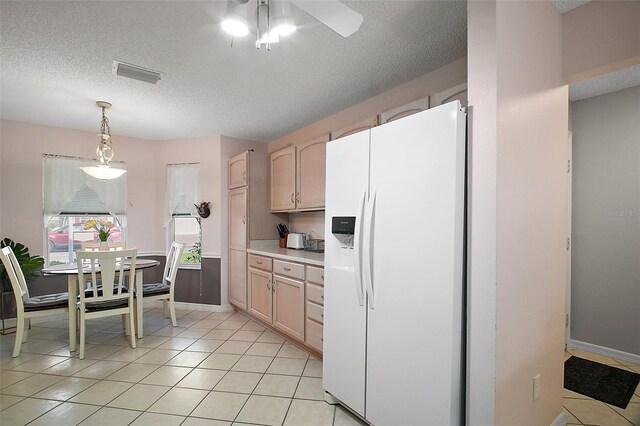 1318 Guerra Ave, The Villages, FL 32159 - kitchen featuring visible vents, light countertops, a textured ceiling, and white fridge with ice dispenser
