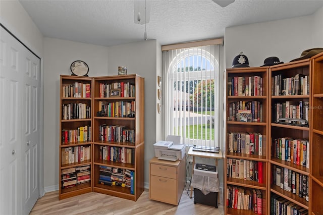5500 Laver St, Leesburg, FL 34748 - sitting room with a textured ceiling, wall of books, and light wood-style flooring