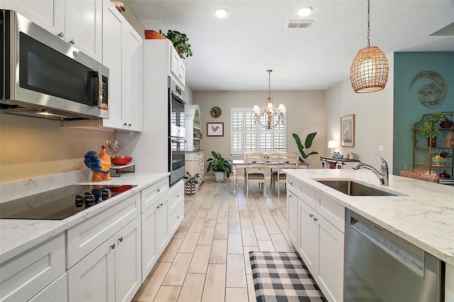 31857 Dahlia Ct, Eustis, FL 32736 - kitchen featuring appliances with stainless steel finishes, a chandelier, a sink, white cabinets, and decorative light fixtures