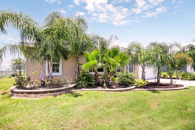 exterior space featuring fence, an attached garage, stucco siding, and a front yard