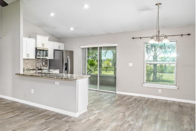 kitchen with stainless steel appliances, a notable chandelier, light stone counters, and light wood-type flooring