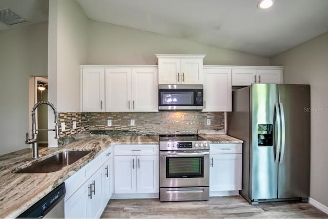 kitchen with a sink, backsplash, stainless steel appliances, and lofted ceiling