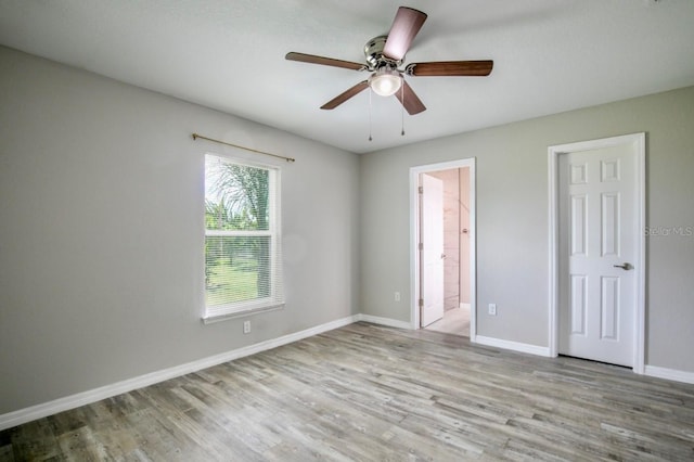 unfurnished bedroom with ceiling fan, baseboards, ensuite bathroom, and wood finished floors