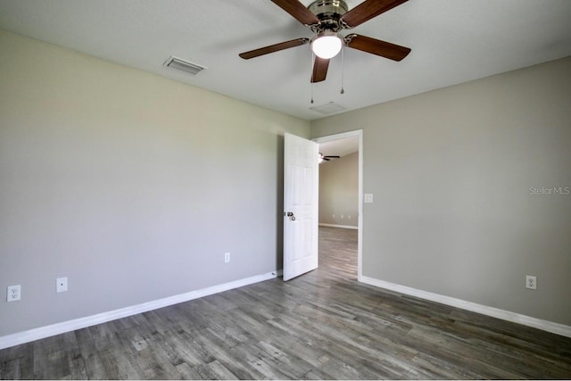 empty room with baseboards, ceiling fan, dark wood-style floors, and visible vents