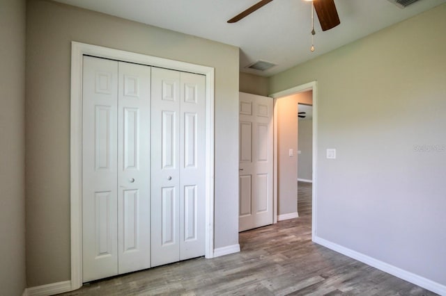 unfurnished bedroom with a ceiling fan, baseboards, wood finished floors, visible vents, and a closet