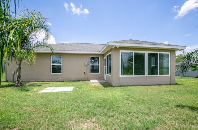 rear view of property featuring a yard and stucco siding