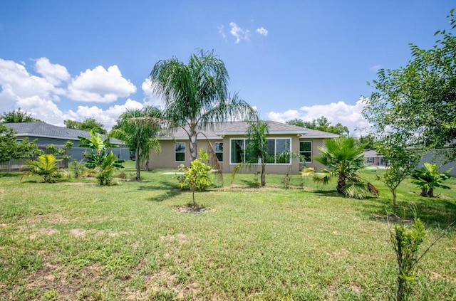 back of property with a lawn and stucco siding