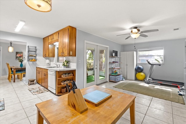 kitchen featuring dishwasher, light countertops, brown cabinetry, a ceiling fan, and light tile patterned floors