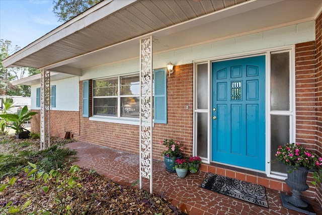 entrance to property with covered porch and brick siding