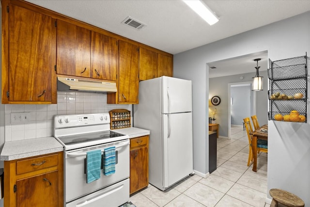 kitchen with white appliances, light countertops, backsplash, under cabinet range hood, and visible vents