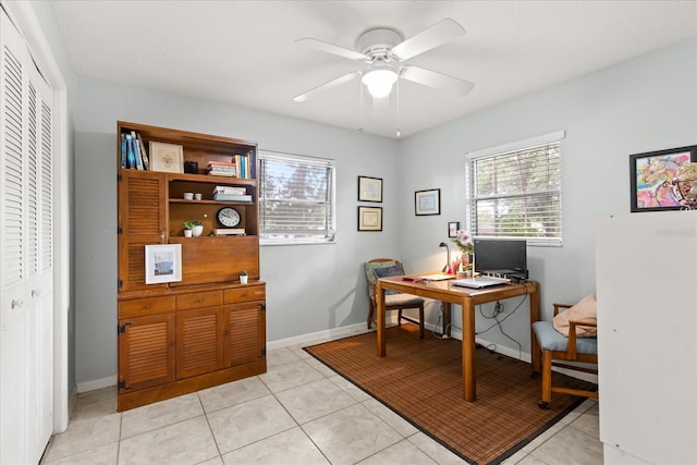 home office featuring a ceiling fan, baseboards, light tile patterned floors, and a healthy amount of sunlight