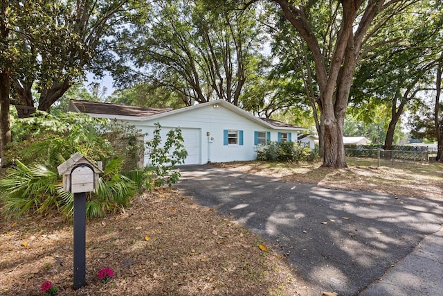 ranch-style home with a garage, fence, and driveway