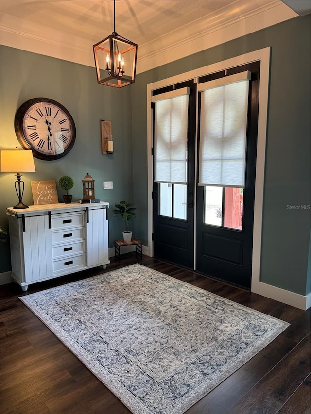 entrance foyer featuring a chandelier, ornamental molding, baseboards, and dark wood-type flooring
