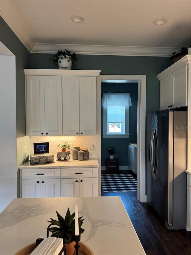 kitchen with stainless steel fridge, white cabinets, and ornamental molding